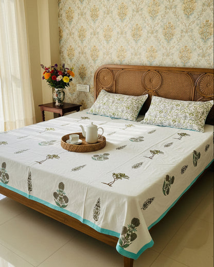 Sage green leaf motif soft fine cotton bedsheet with an aqua border styled on a cane headboard bed