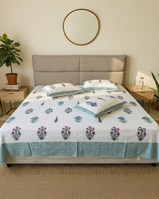 Bed with floral patterned bedspread and pillows in a room.