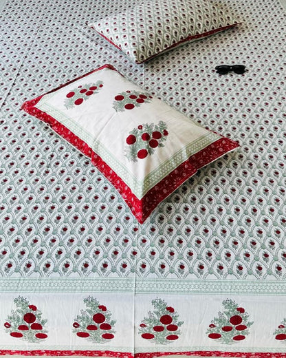 Close-up of sage green jaal cotton fabric with red floral bouquets and pillow covers