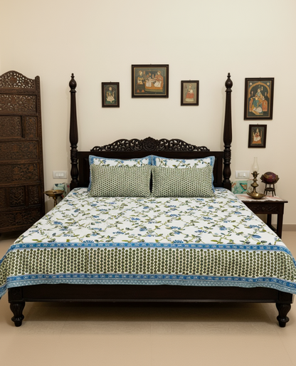 Blue floral cotton bedsheet on a carved four-poster bed with green dotted pillow covers
