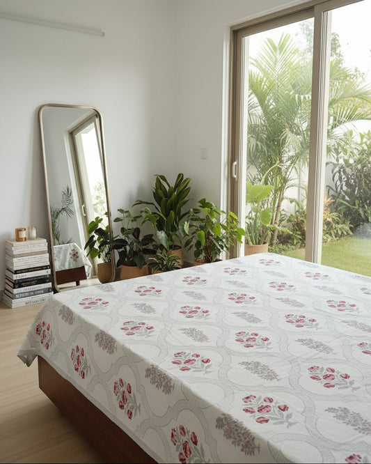 Bedroom with floral bedspread, plants, and a large mirror.