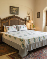 Yellow and pink floral booti cotton bedsheet with a grey border on a carved wooden bed