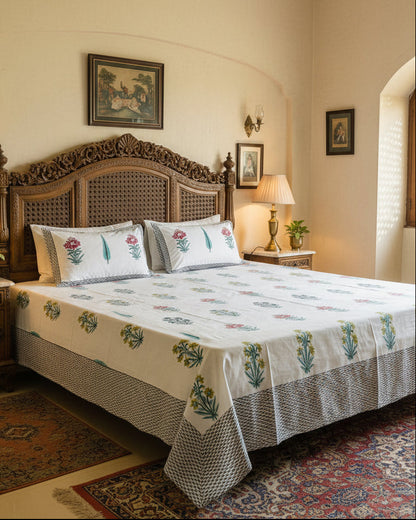 Yellow and pink floral booti cotton bedsheet with a grey border on a carved wooden bed